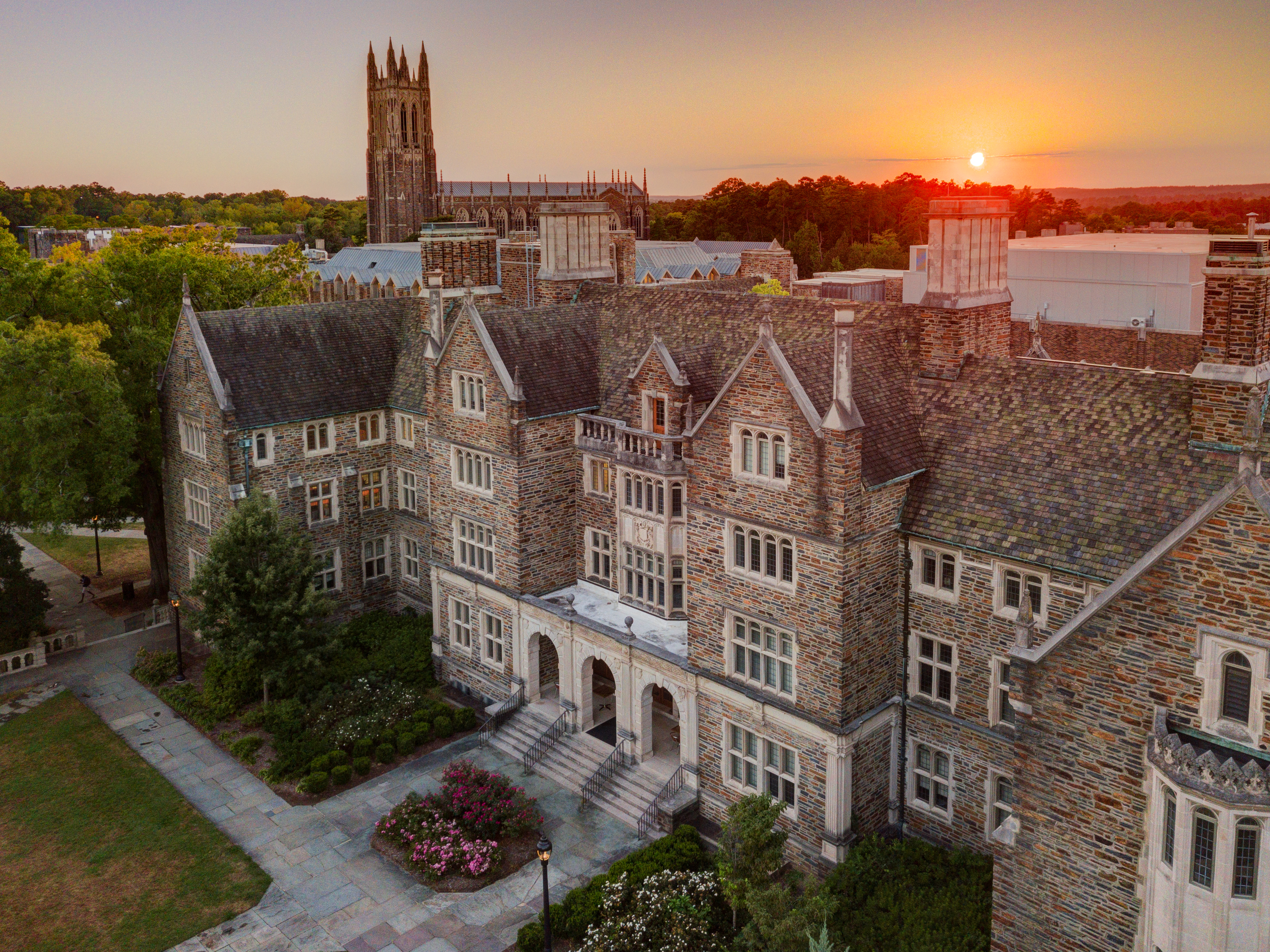 A picture of the sun setting over the Duke University chapel and other buildings on campus.